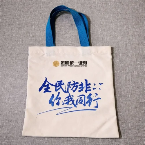 canvas-tote-bag-printing-singapore-corporate-logo Canvas tote bag printing Singapore with custom corporate logo and blue handles.