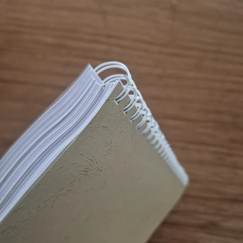 Close-up of coil bound book with white spiral binding and textured cover, showing durable and professional finish.
